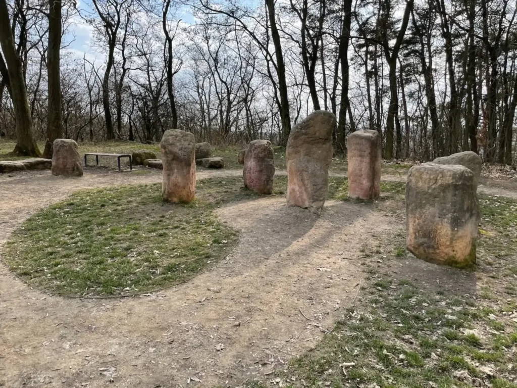 Kamenný kruh u rozhledny v Úvalech obklopený lesem.