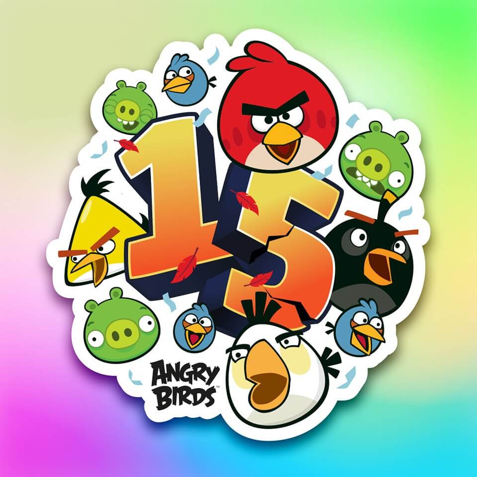 Veselá ilustrace oslavující 15. výročí hry Angry Birds s číslem 15 v popředí, obklopeném různými postavami z hry, včetně červeného, žlutého, bílého ptáka a zelených prasat. Pozadí má jemný barevný gradient.