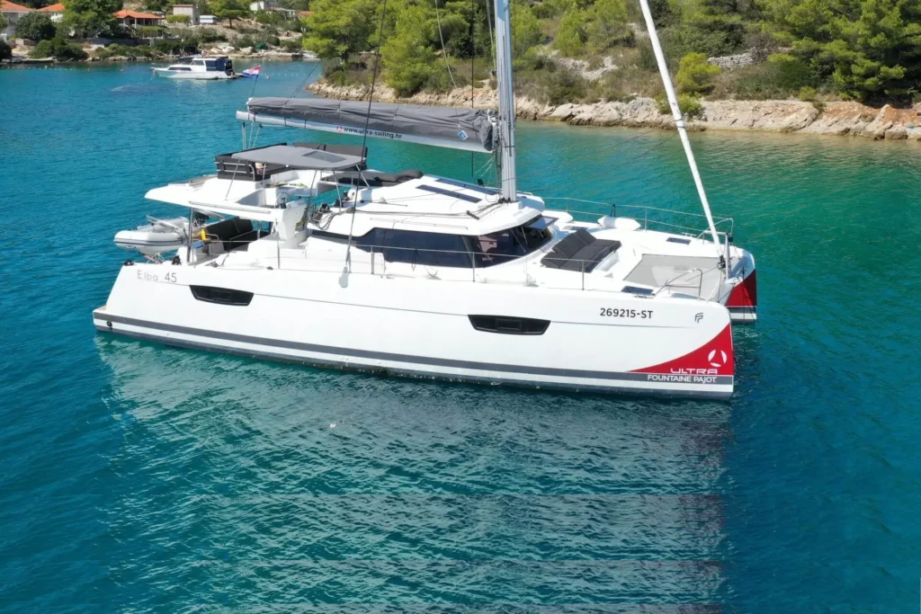 Moderní katamarán Elba 45 kotvící v tyrkysové zátoce v Chorvatsku, připravený k pronájmu pro dovolenou na moři.