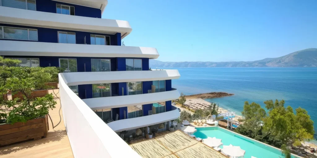 Moderní budova hotelu Regina Blue v Albánii s výhledem na Jaderské moře, pláž a bazén z horní terasy.