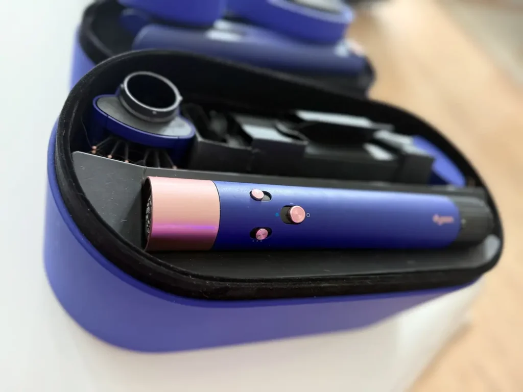 Detail přístroje Dyson Airwrap Long v barvě růžové a modré v otevřeném pouzdře s nástavci