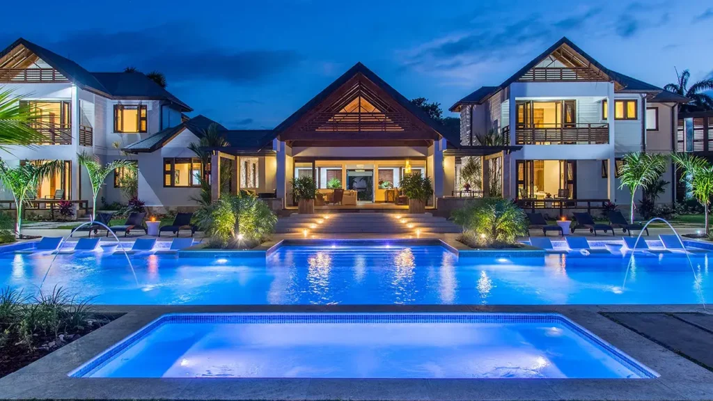Luxusní vila s osvětleným bazénem a zahradou při večerním pobytu