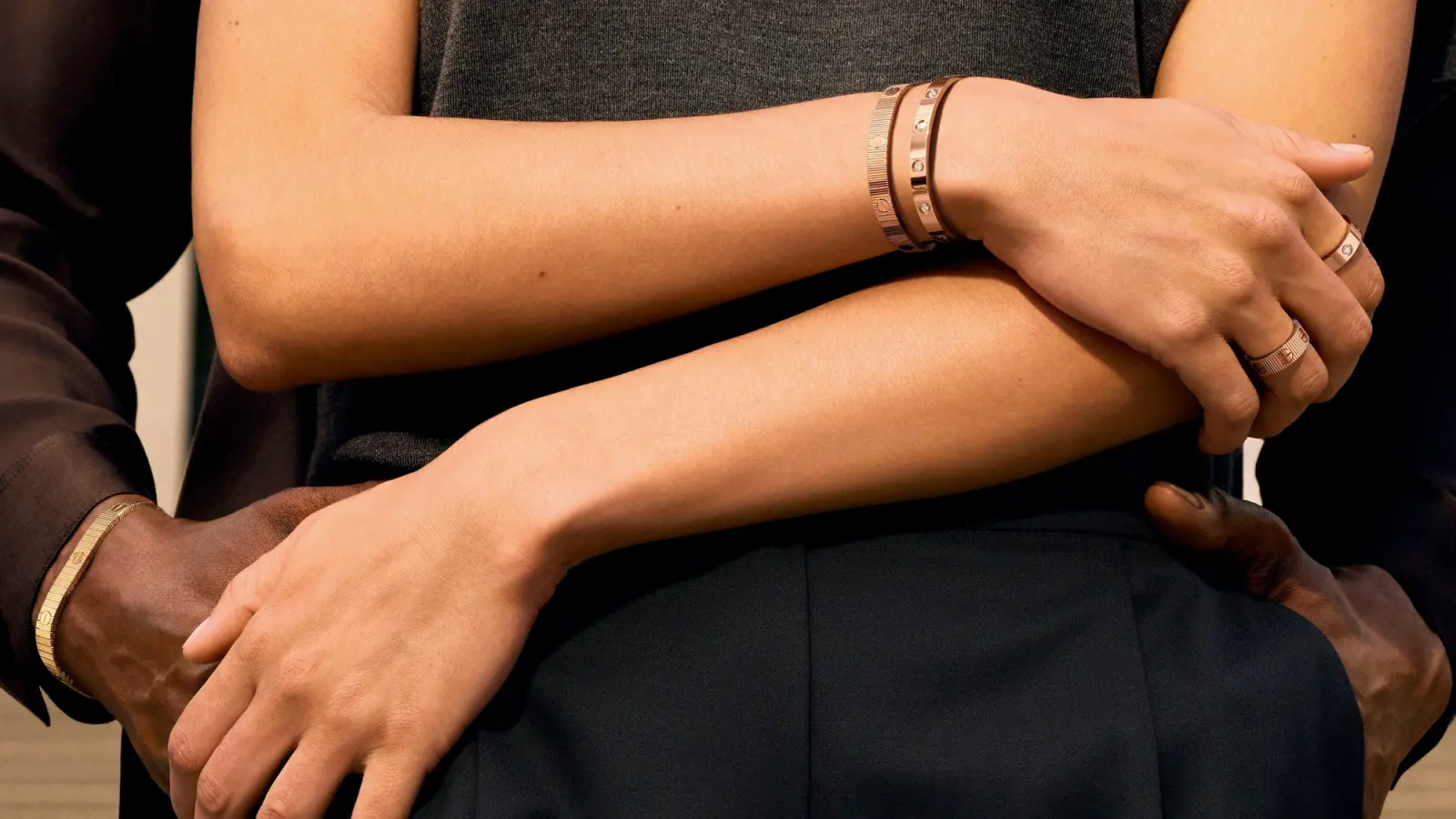 Pár objímající se, na zápěstích oba nosí Cartier LOVE UNLIMITED – šperk jako vyjádření blízkosti a něhy.