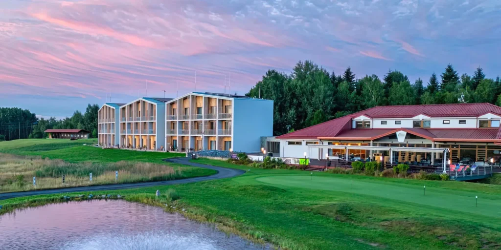 Pohodový pohled na Marshall Golf & Wellness Hotel v Dolním Rychnově při západu slunce – moderní hotel, restaurace a zelené golfové hřiště hned za oknem.