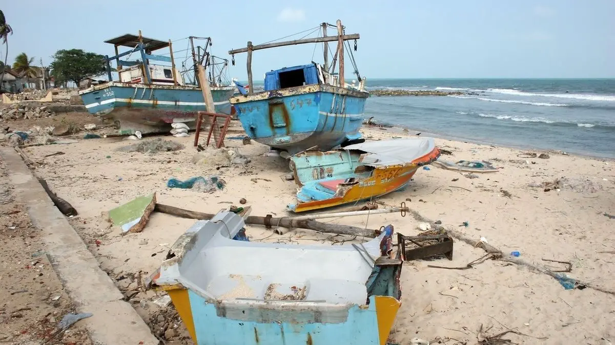 Rozbité rybářské lodě vyhozené na pláž po zemětřesení. Všude trosky a ticho po obrovské síle moře.