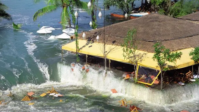 Obrovská vlna zaplavuje restauraci u moře, stoly a židle mizí pod vodou. Všechno se mění v chaos během pár vteřin.