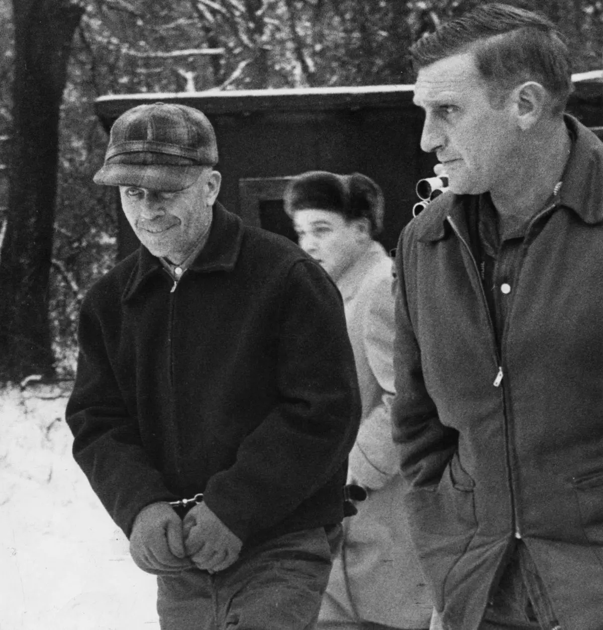 Edward Gein v poutech během eskorty zasněženou krajinou, doprovázen policistou