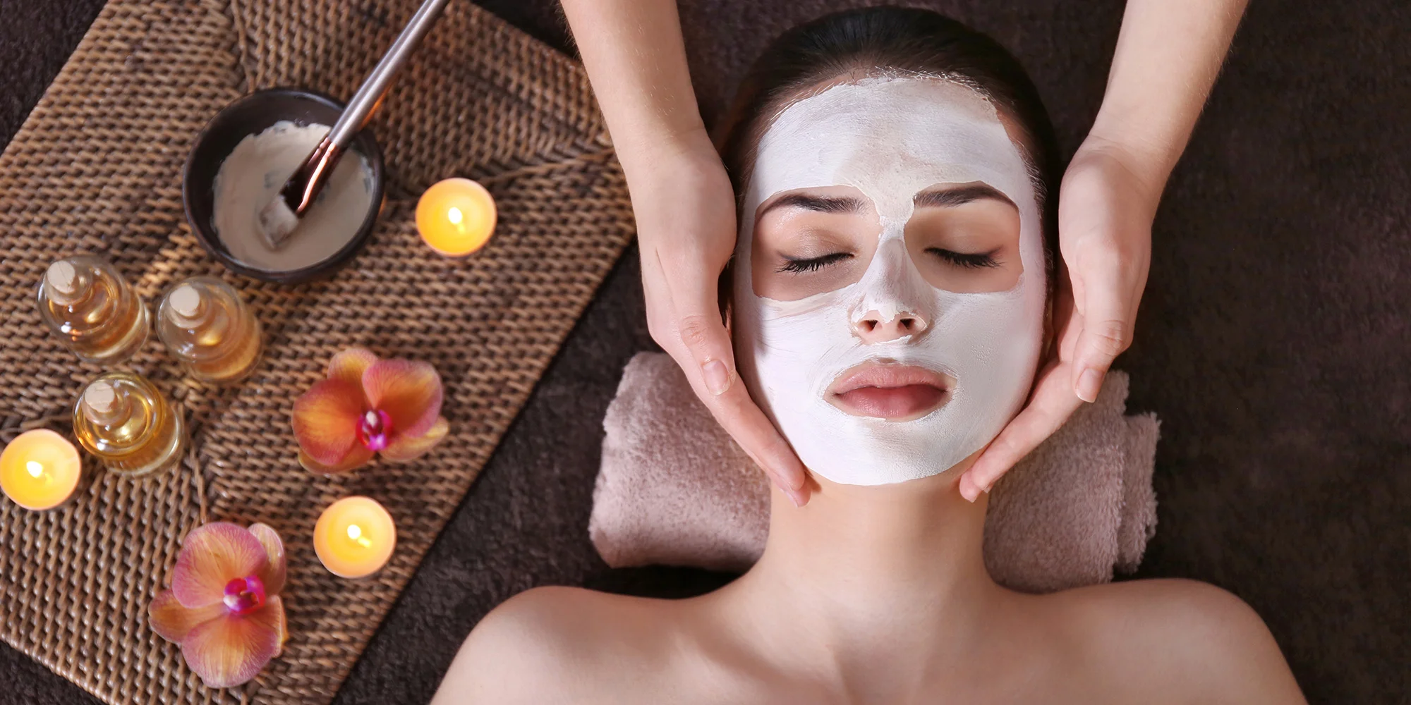 Žena s pleťovou maskou a rukama kosmetičky na obličeji při relaxaci ve studiu