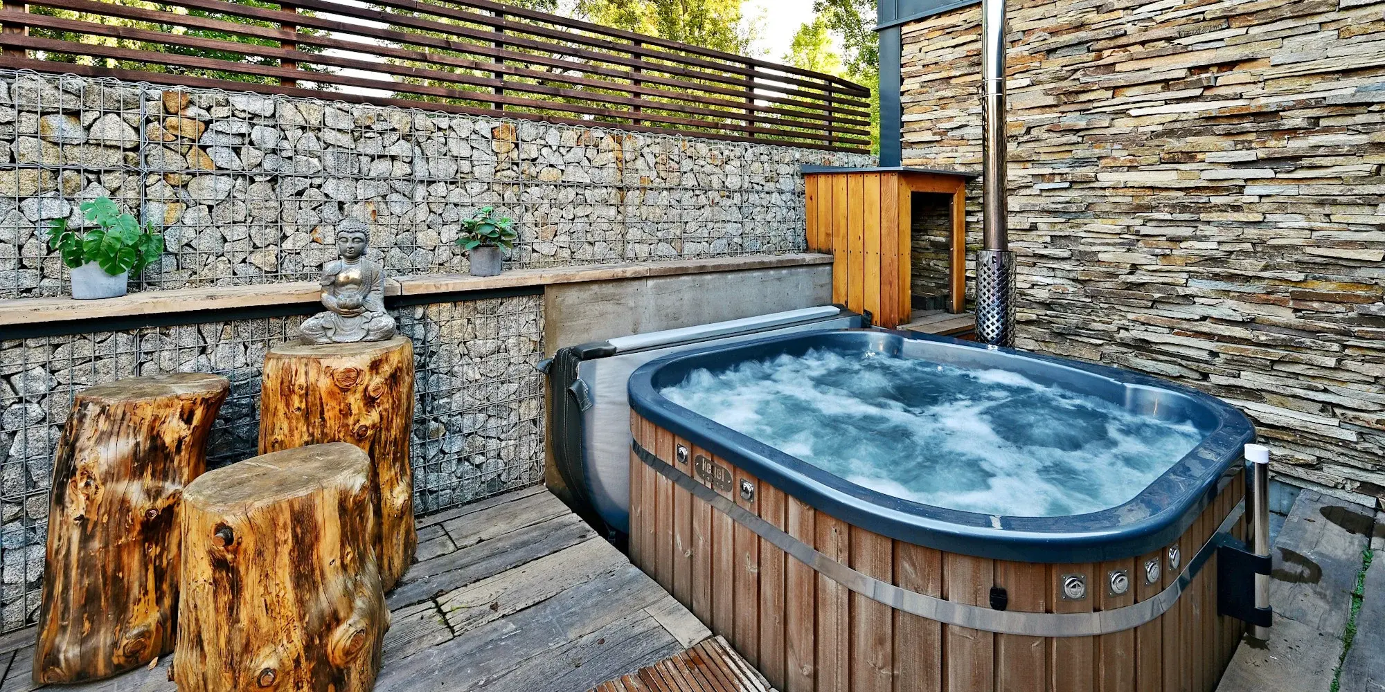 Privátní wellness vířivka s výhledem do přírody, obklopená dřevem a kamenem