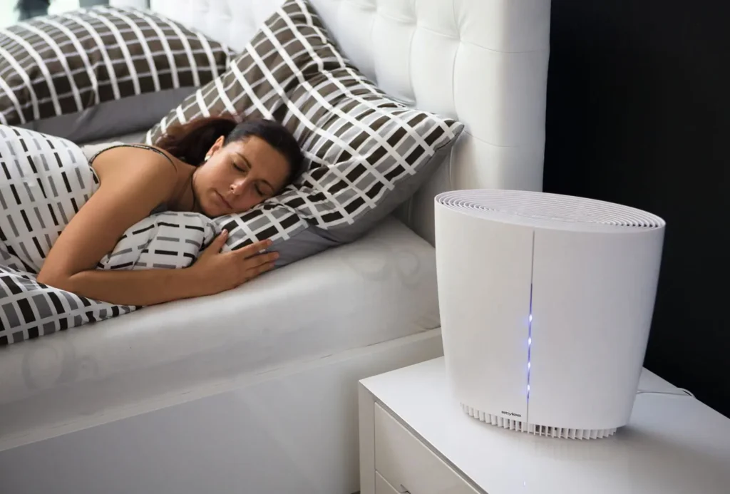 Spící žena v ložnici vedle čističky vzduchu Stylies, která běží v nočním režimu.
