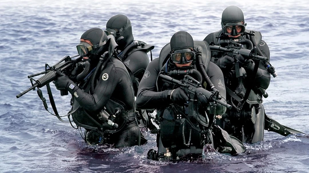 Potápěči Navy SEALs vycházejí z moře během tajné operace.