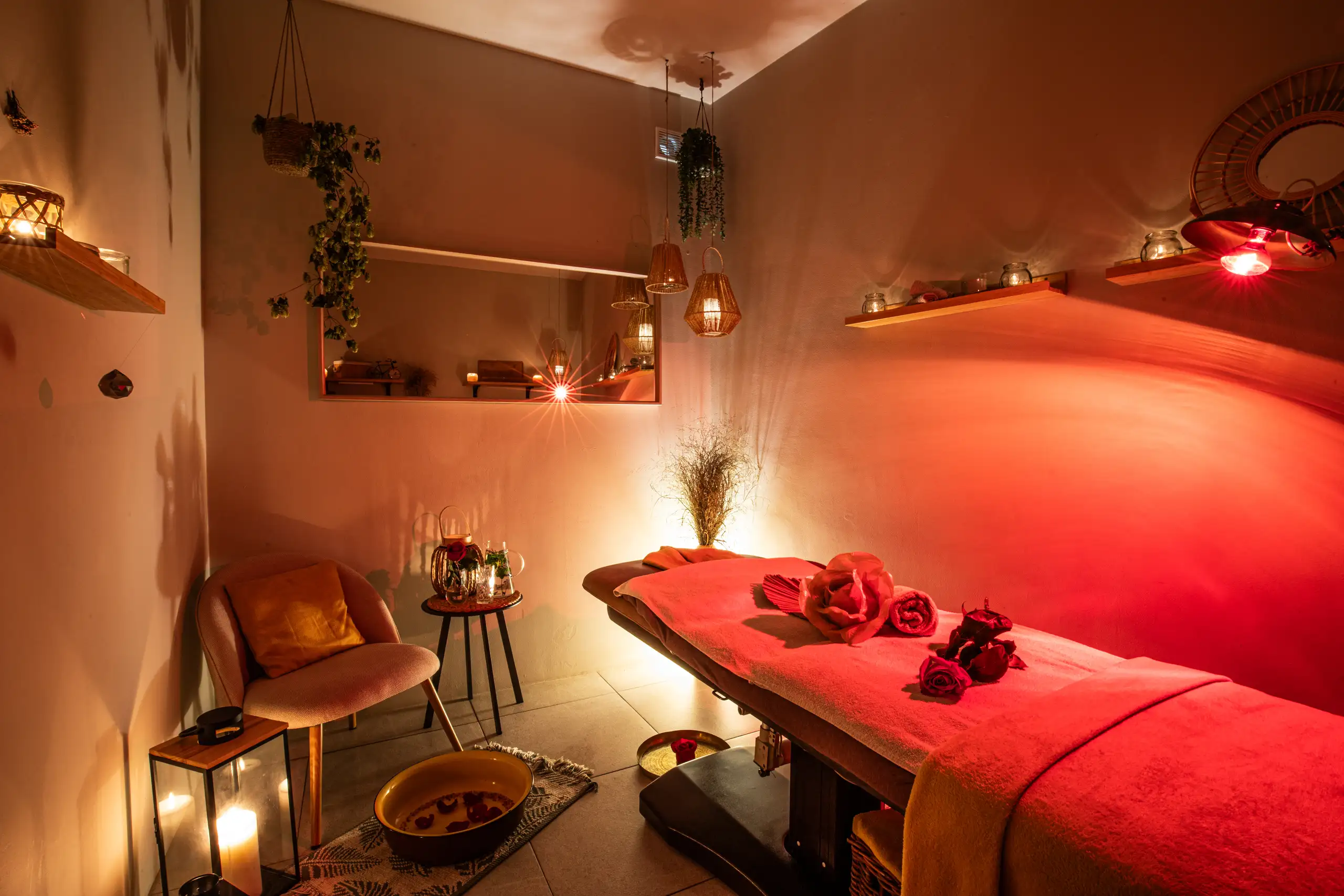 Útulná wellness místnost s tlumeným světlem, svíčkami a masážním lehátkem
