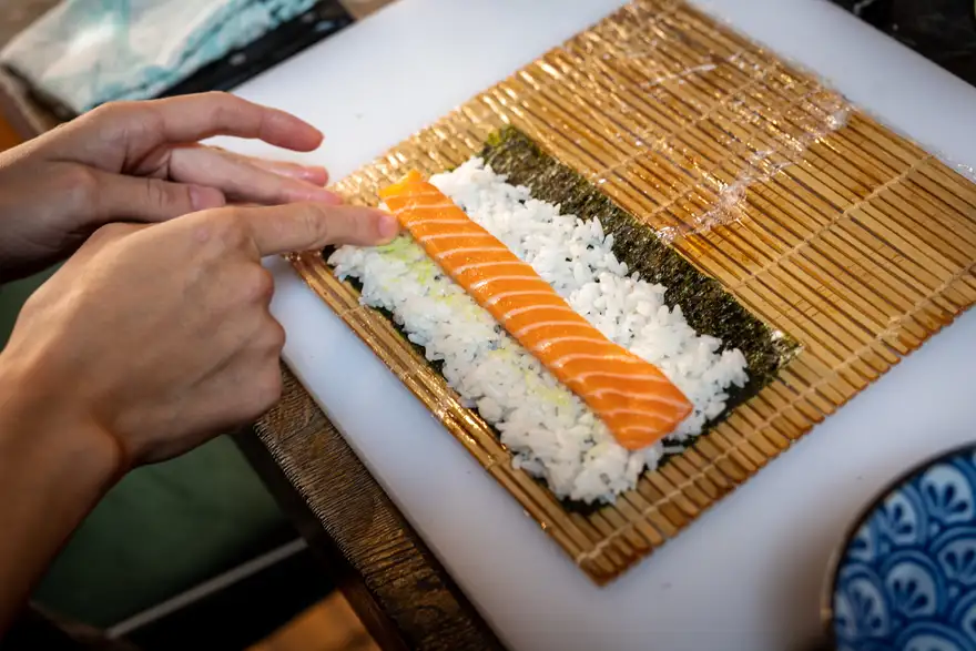 sushi | Venclíkovi.cz Detail přípravy sushi na bambusové podložce s čerstvým lososem a rýží