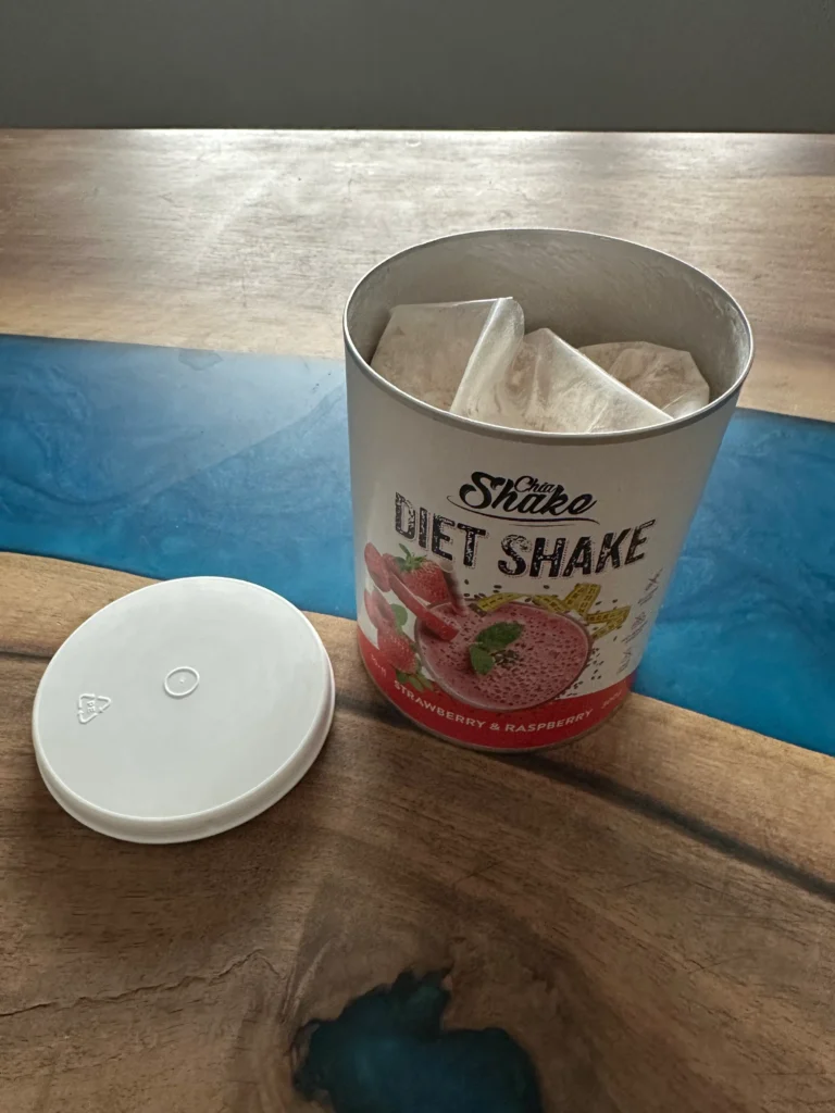 IMG_8961 | Venclíkovi.cz Otevřené balení Chia Shake s nasypaným obsahem uvnitř a víčkem položeným vedle.