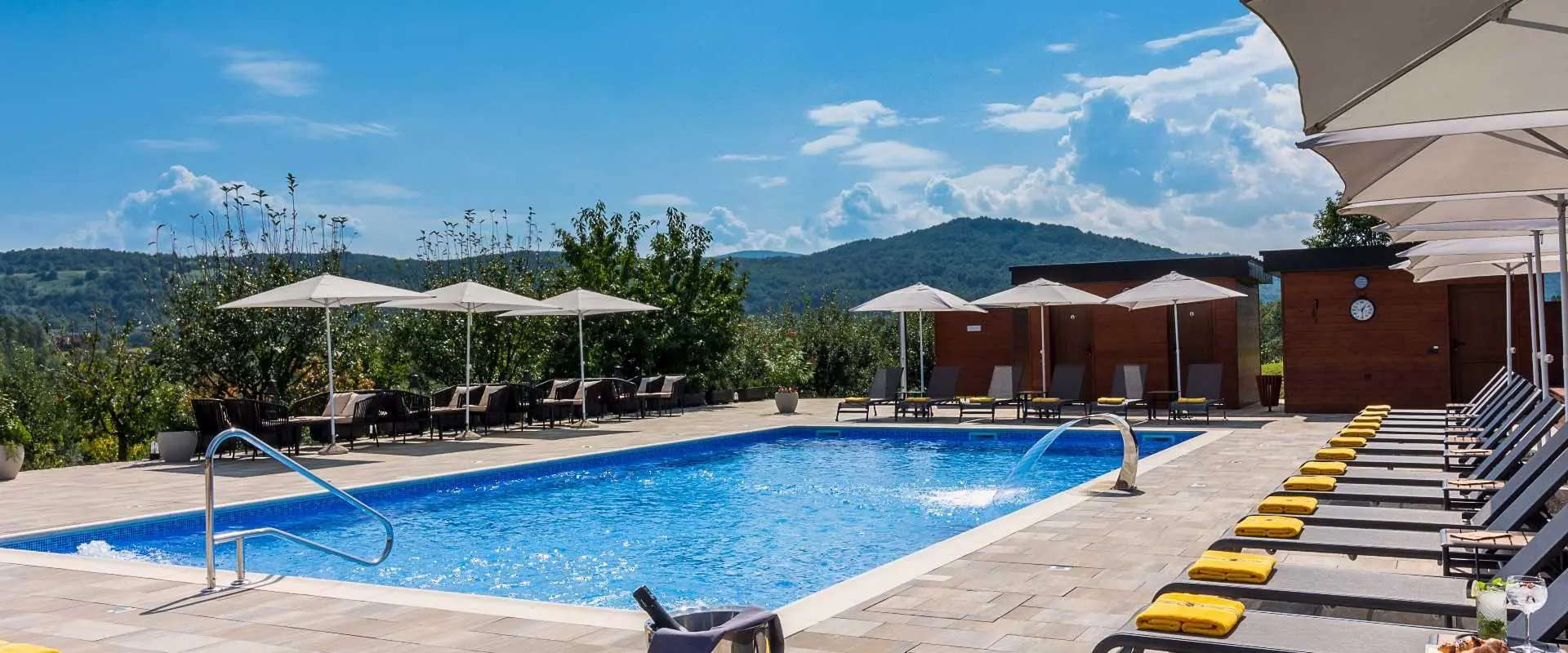 Hotel Degenija | Venclíkovi.cz Venkovní bazén hotelu Degenija s výhledem na kopce a relaxační zónou