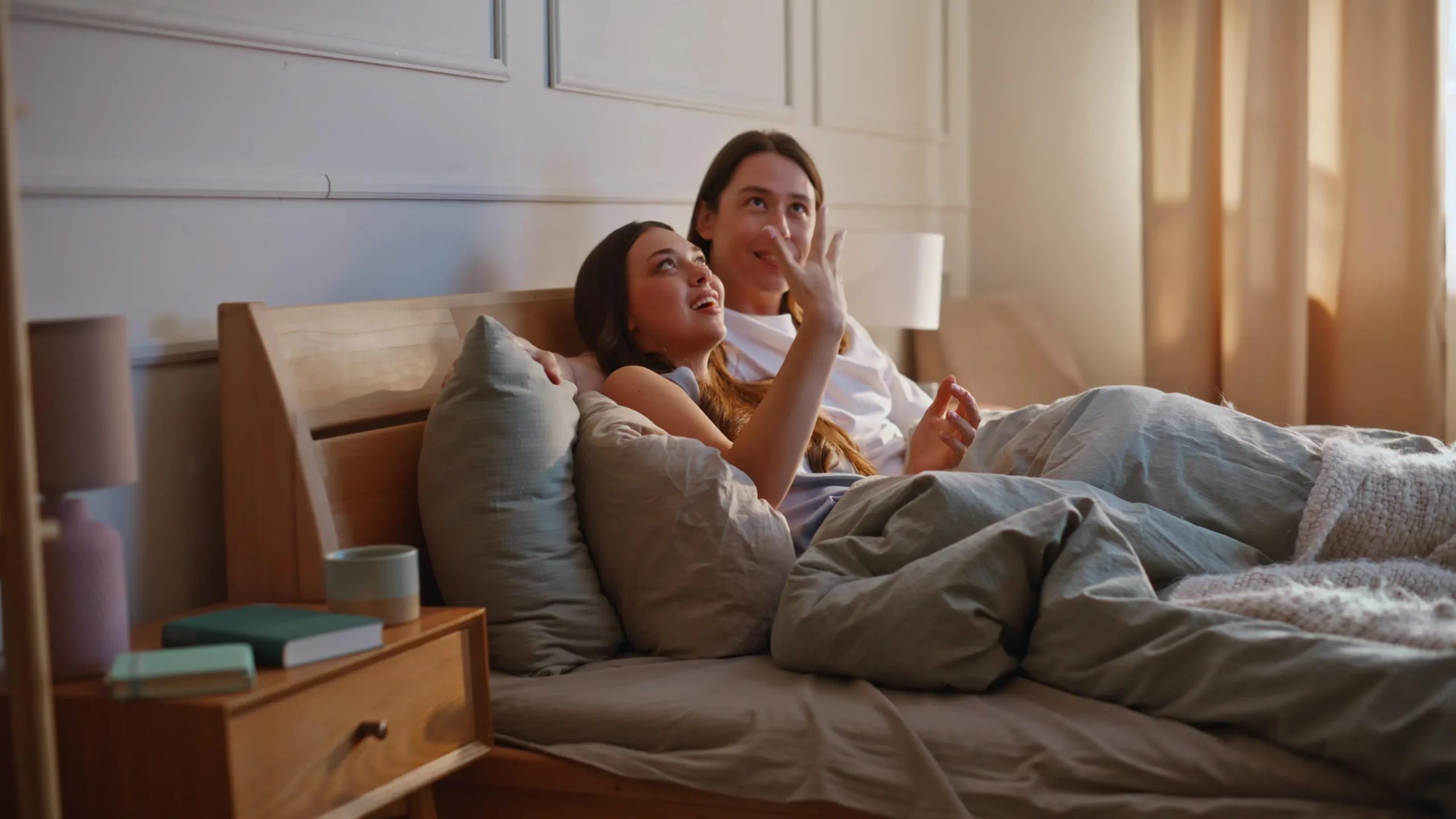 jen vedle sebe | Venclíkovi.cz Pár leží spolu v posteli, povídají si a smějí se v klidné večerní atmosféře ložnice.