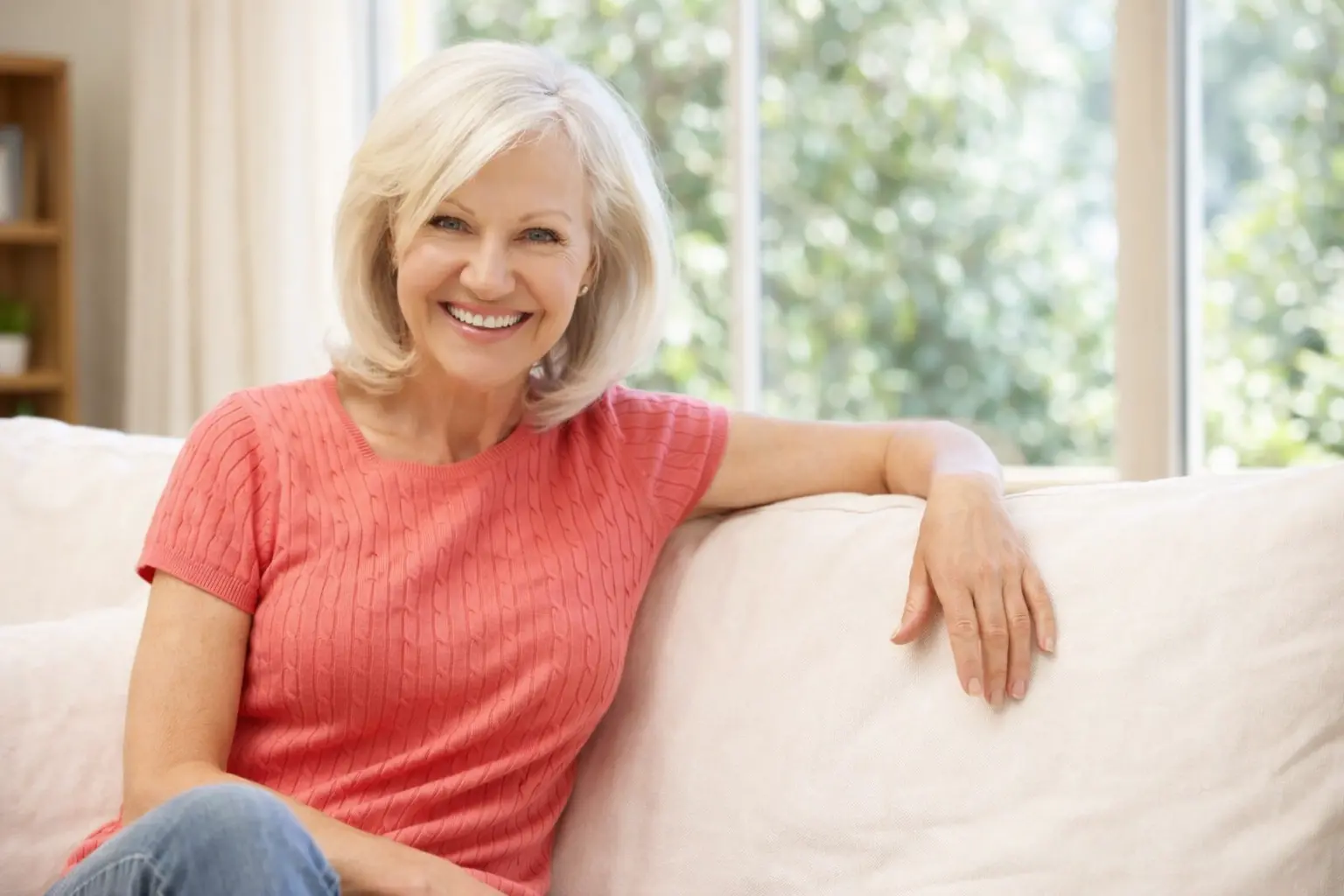 zena obyvak | Venclíkovi.cz Usměvavá žena po padesátce sedí na pohovce v prosvětleném obýváku a působí klidně a sebevědomě.