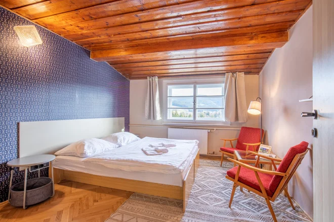 Pokoj s manželskou postelí a dřevěným stropem v aparthotelu Panorama