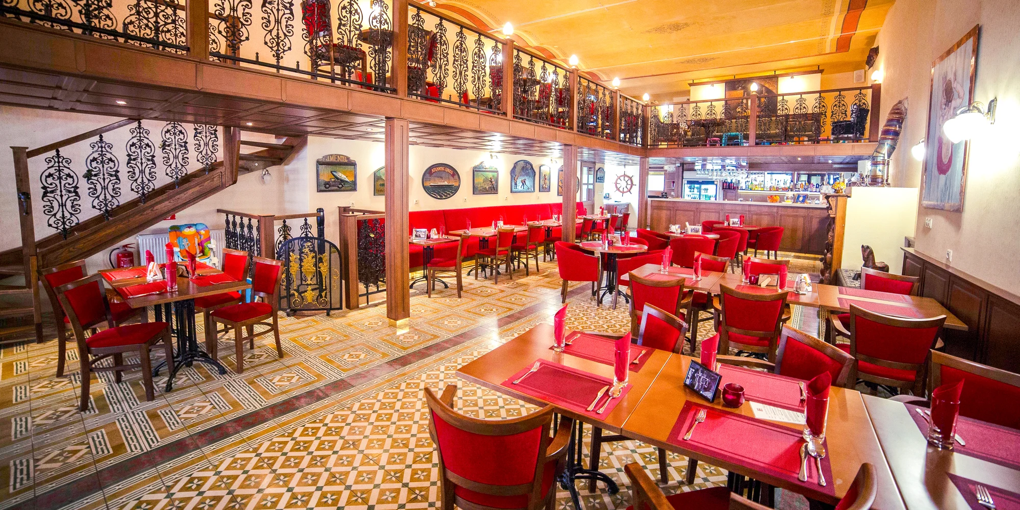 Restaurace hotelu Bristol s dřevěnou galerií a červenými křesly