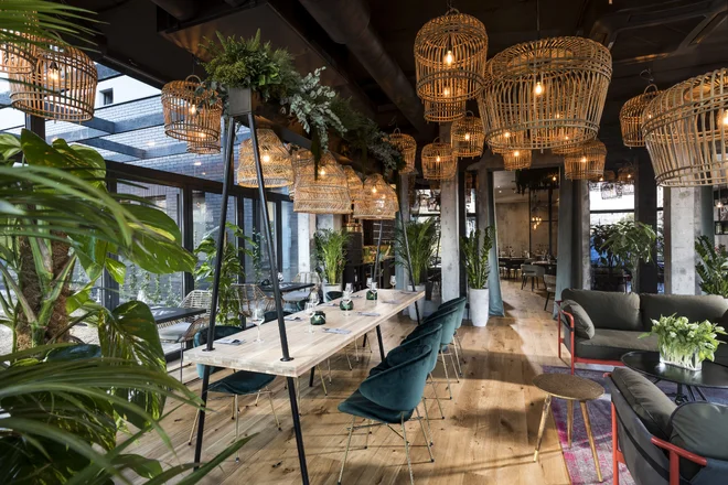 Restaurace hotelu Sadova s proutěnými svítidly, zelenými křesly a rostlinami