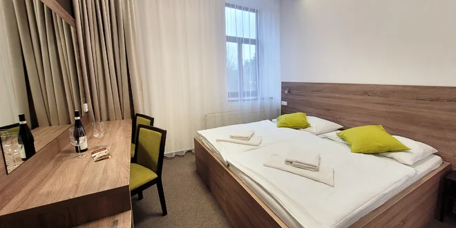 Dvoulůžkový pokoj hotelu Broušek s dřevěným nábytkem a zelenými polštáři