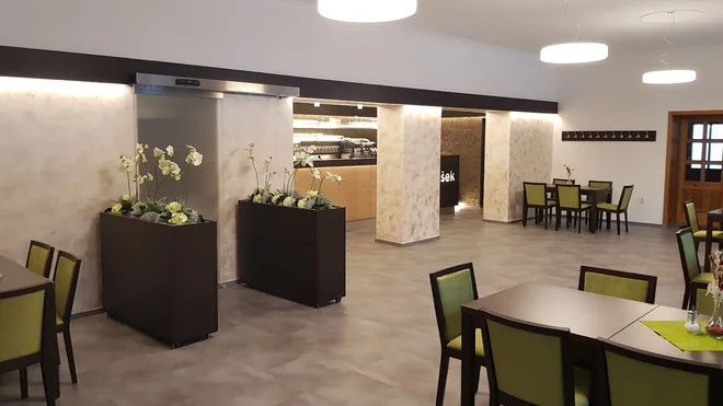 Restaurace hotelu Broušek se zelenými židlemi a barem