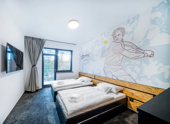 Dvoulůžkový pokoj hotelu Break s kresbou tenisty na stěně