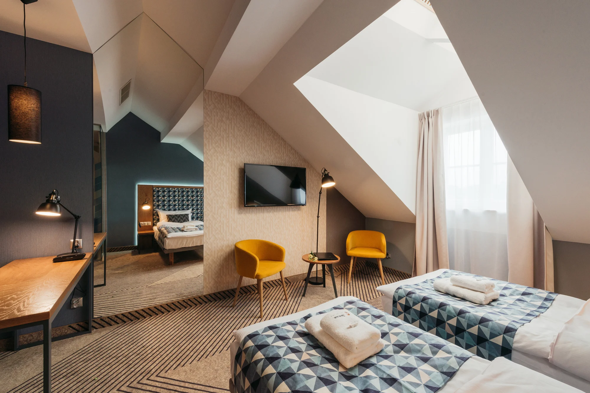 Dvoulůžkový pokoj hotelu Avena v Krakově se žlutými křesly a šikmým stropem