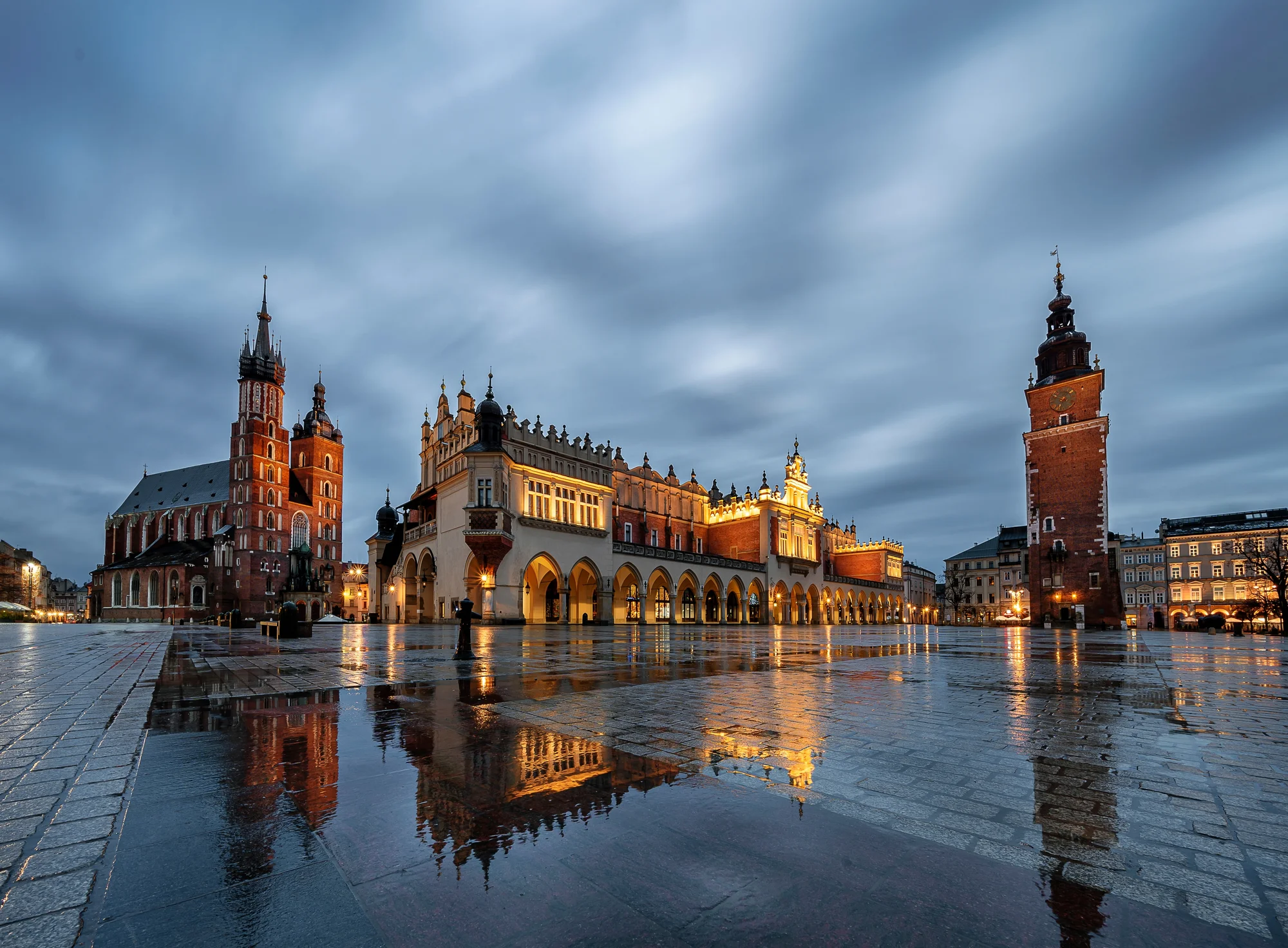 Večerní Rynek Główny v Krakově s tržnicí Sukiennice, Mariánským kostelem a radniční věží