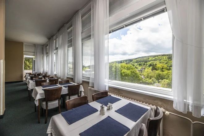 Stoly restaurace hotelu Harmonie u oken s výhledem do zeleně