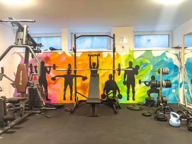 Posilovací stroje a činky v barevně vymalovaném fitness Kampus Palace