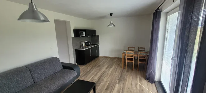 Obývací pokoj apartmánu Pod Bukovkou s pohovkou, kuchyňským koutem a jídelním stolem