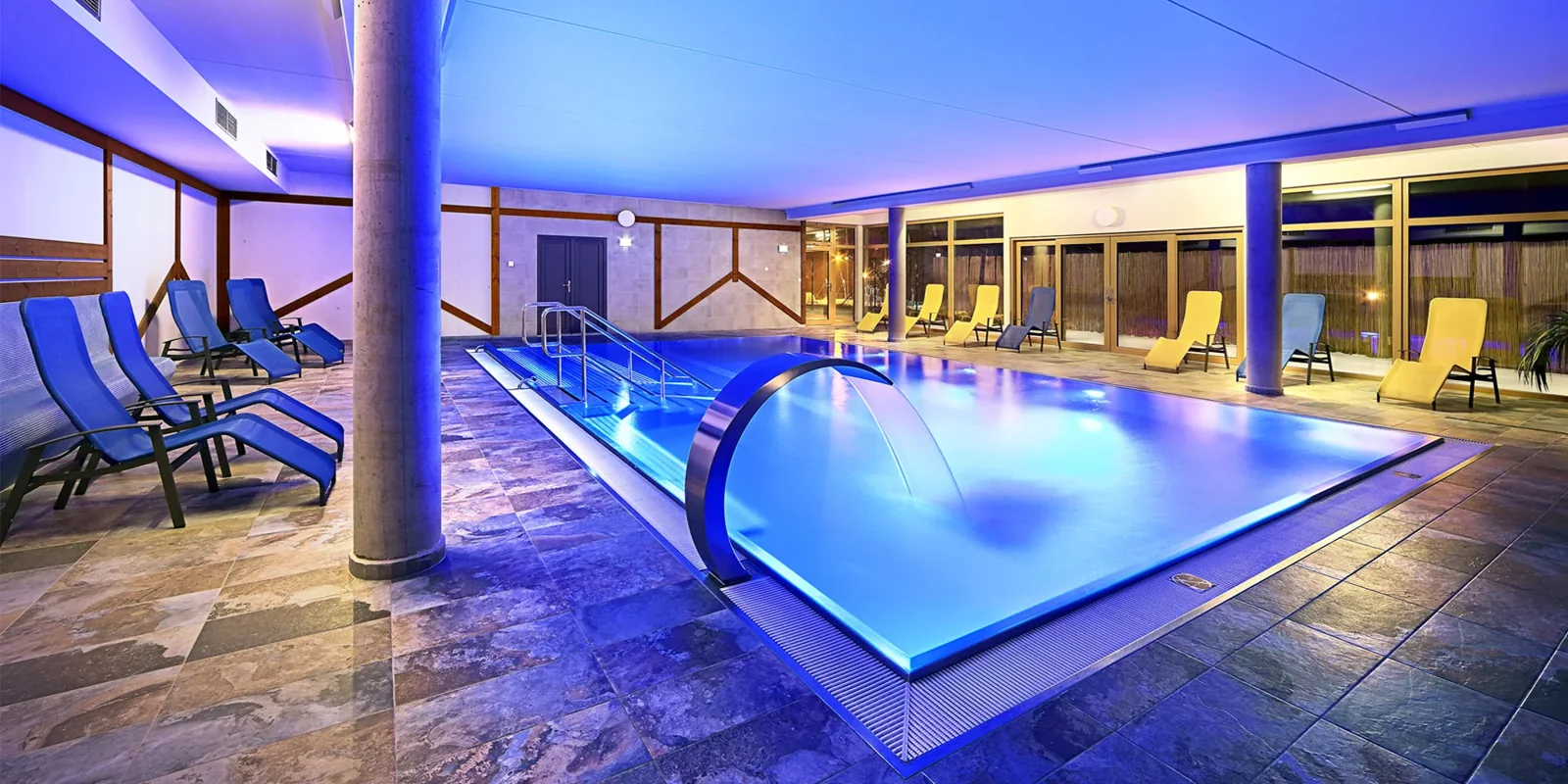 Osvětlený vnitřní bazén s lehátky ve wellness Resortu Relax u Lipna