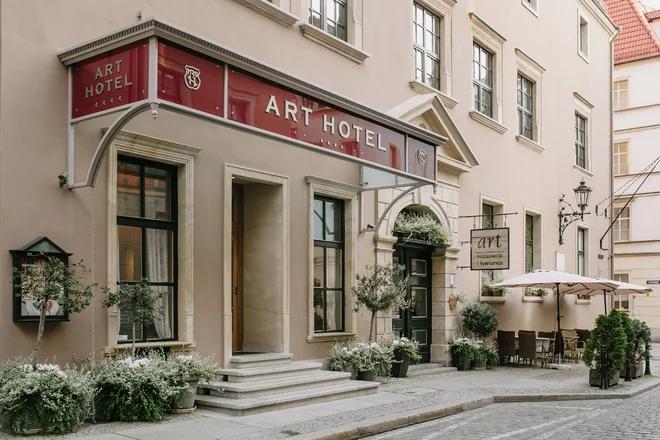 Vchod do Art Hotelu ve Vratislavi s červeným označením a zelení před historickou fasádou