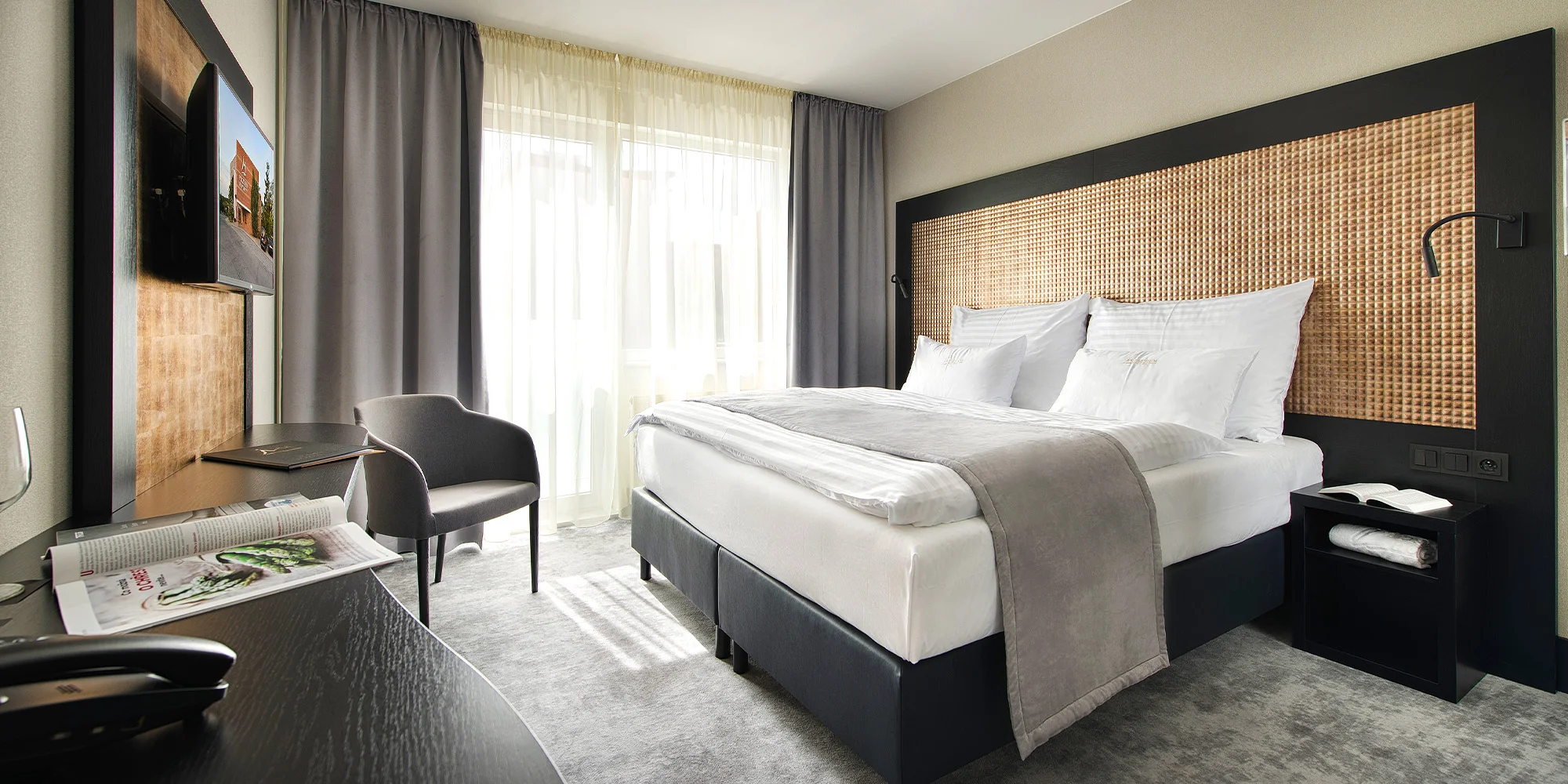 Pokoj Comfort s dvoulůžkem a šedým křeslem v Premium Hotelu ve Znojmě