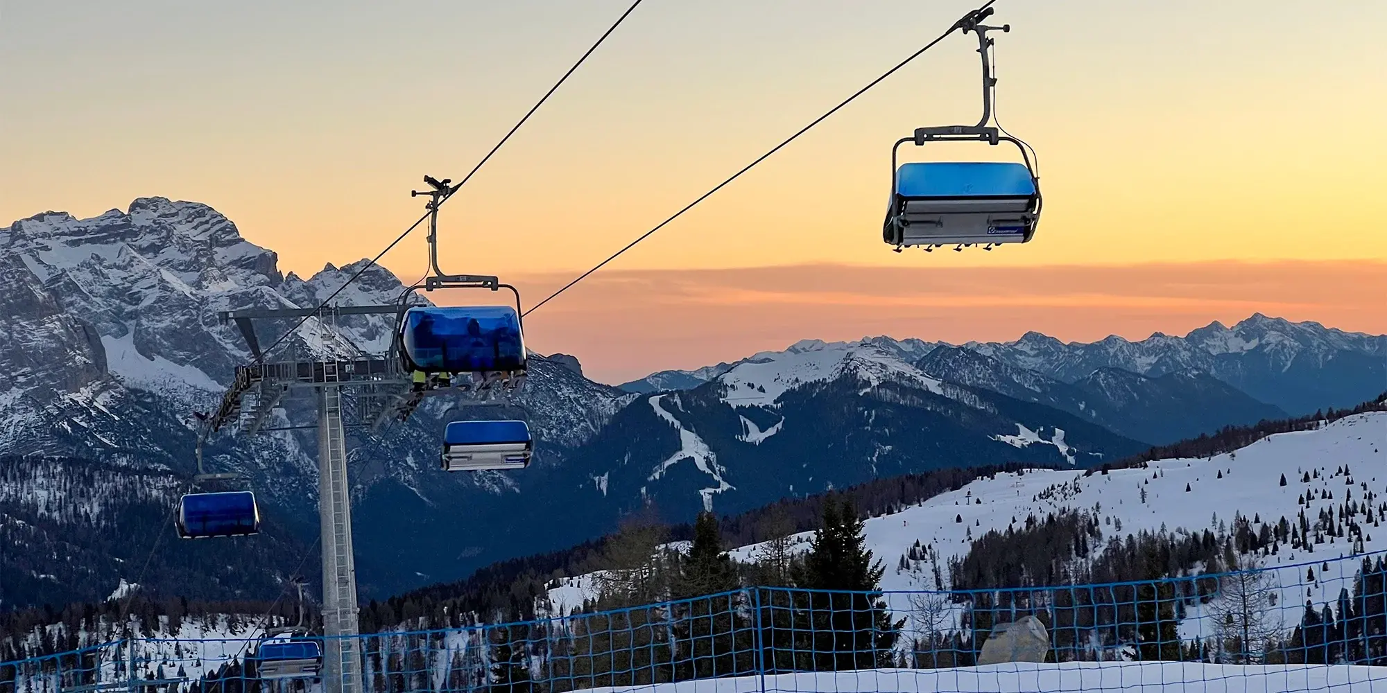 Lanovka nad zasněženými Dolomity při západu slunce
