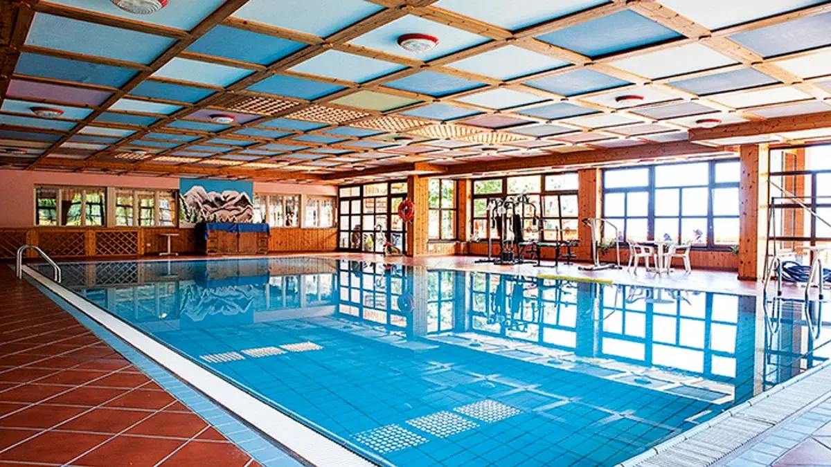 Krytý bazén v hotelu Sancamillo s lehátky a dřevěným vybavením