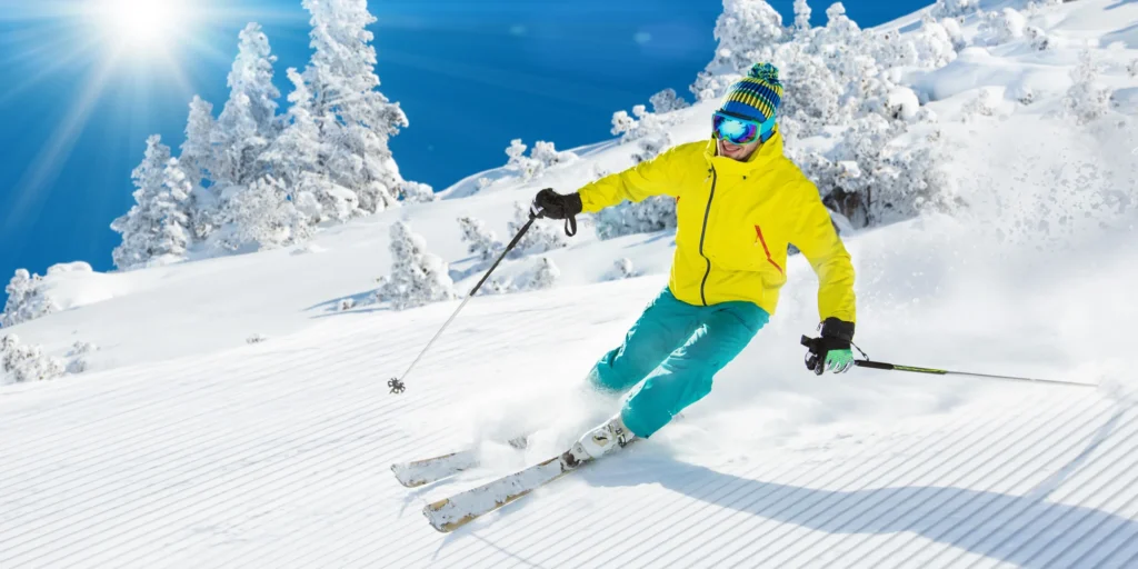 Lyžař si to sviští po čerstvě urolbovaném manšestru za parádního slunečného dne.